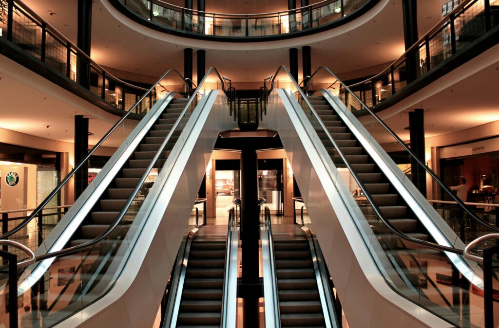 Projects Symmetrical view of escalators in a modern shopping mall interior, showcasing architecture and design.
